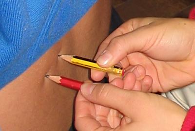 una persona punge la schiena di un'altra con due matite