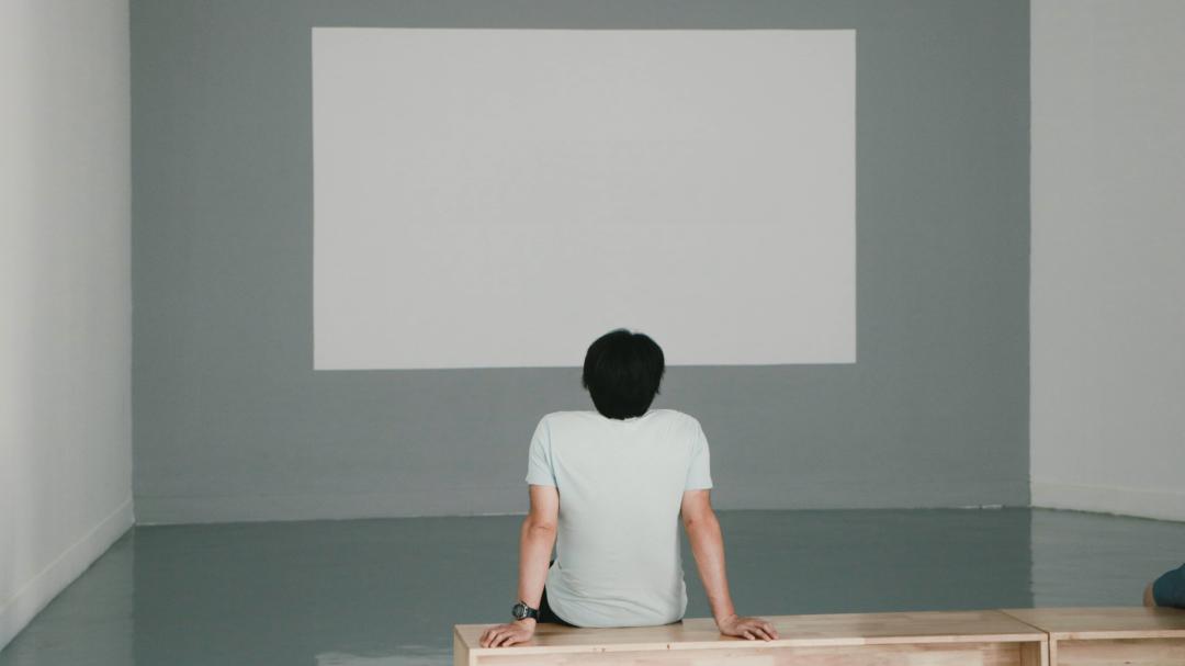 Un uomo guarda un quadro completamente bianco appeso ad una parete