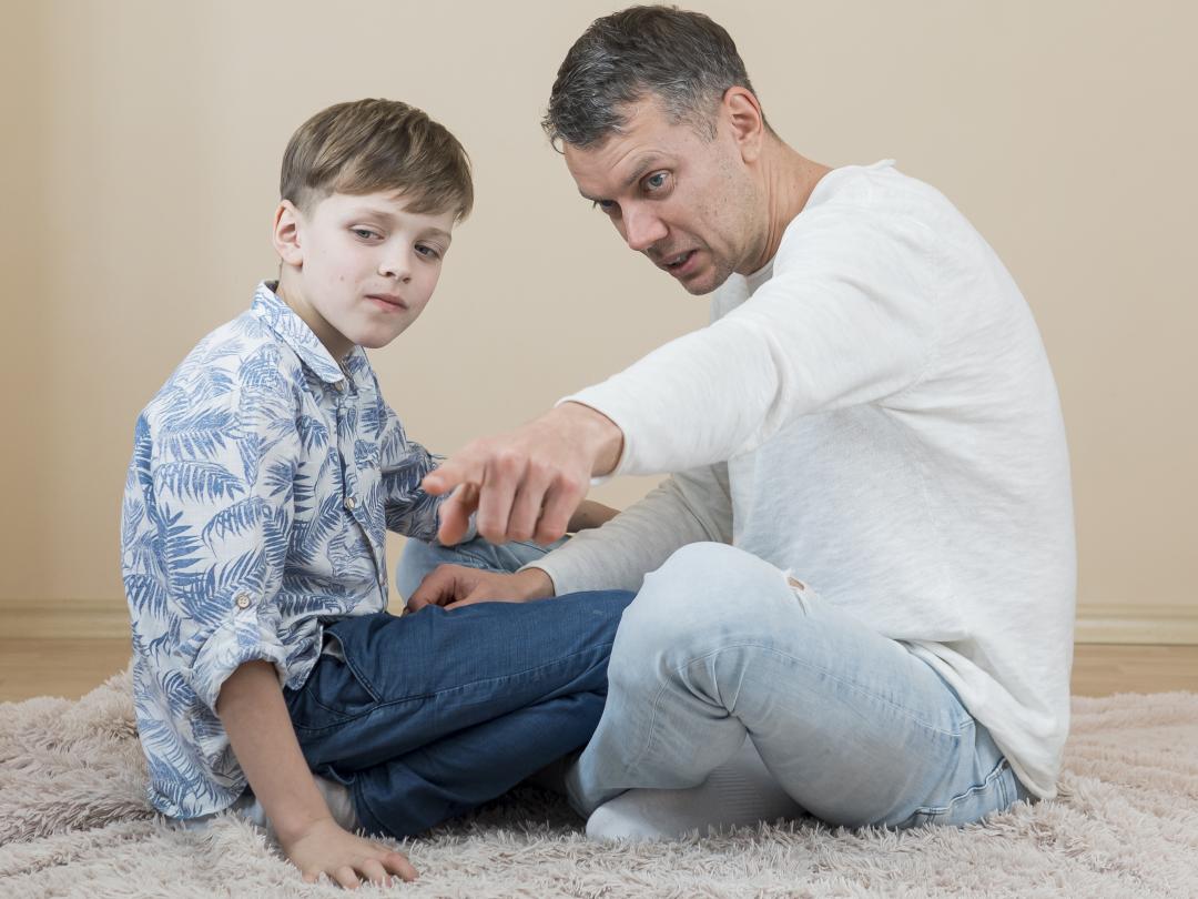 il padre seduto a terra indica qualcosa al figlio